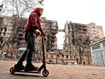 南部の港湾都市マリウポリでのウクライナとロシアの紛争で破壊された建物の近くで、少年がスクーターに乗っています。 ロイター