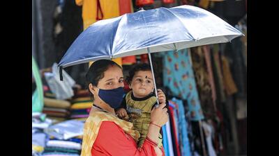 A woman with a child holds an umbrella to shield themselves on a hot summer day in Jammu on Friday. (PTI)