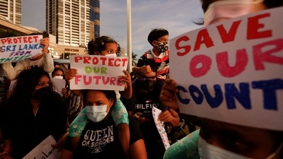 Children holding placards are carried by their guardians as they take part during the protest against Sri Lankan President Gotabaya Rajapaksa. (Reuters)