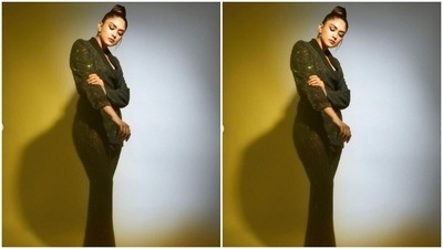 Mrunal paired a full-sleeved midriff-baring black long blazer with a pair of satin trousers with wide legs. Mrunal's blazer came with collared details and a tie-around closure at the waist. (Instagram/@mrunalthakur)