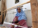 A Tunisian craftswoman weaves a rug at a workshop run by Shanti, a social enterprise that helps artisans from across the North African country (FETHI BELAID AFP)