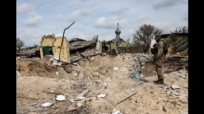 A Ukranian serviceman looks into a crater and a destroyed home are pictured in the village of Yatskivka, eastern Ukraine on April 16, 2022 (AFP) A Ukranian serviceman looks into a crater and a destroyed home are pictured in the village of Yatskivka, eastern Ukraine on April 16, 2022 (AFP)