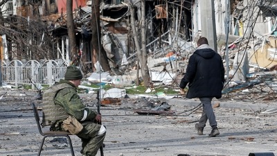 A service member of pro-Russian troops sits on a chair in a street near a building, which was destroyed during Ukraine-Russia conflict in the southern port city of Mariupol, Ukraine. (REUTERS)