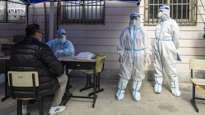 Workers in personal protective equipment keep watch as residents take part in a round of Covid-19 testing during a lockdown in Shanghai, China, on Monday. (Bloomberg)