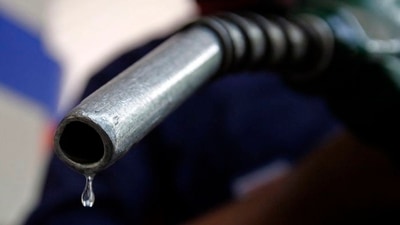 A worker holds a fuel nozzle at a petrol pump in Mumbai&nbsp; (REUTERS)