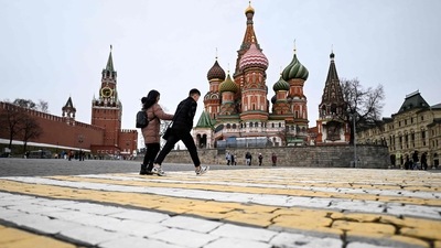 A couple walk in front of the Kremlin's Spasskaya tower and St Basil's cathedral in downtown Moscow. (AFP)