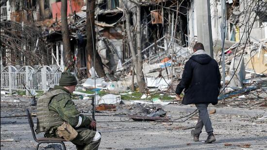 A service member of pro-Russian troops sits on a chair in a street near a building, which was destroyed during Ukraine-Russia conflict in the southern port city of Mariupol, Ukraine (REUTERS)
