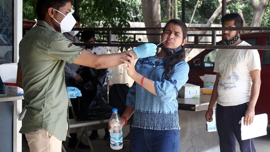 A healthcare worker collects the swab sample of a woman for Covid-19 testing, in Gurugram on Monday. (ANI)(HT_PRINT)