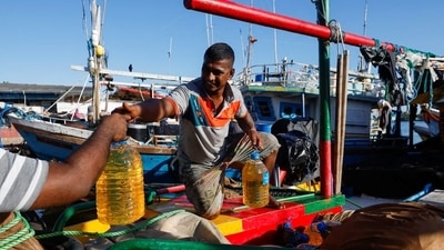 A man gives a bottle of fuel to his friend from a fishing trawler parked at Sri Lanka's Negombo's "Lellama" fishery harbour, as fishermen and their families struggle due to a lack of diesel and a price hike. REUTERS/Navesh Chitrakar (REUTERS)