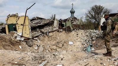 TOPSHOT - A Ukranian serviceman looks into a crater and a destroyed home are pictured in the village of Yatskivka, eastern Ukraine (Photo by RONALDO SCHEMIDT / AFP) (AFP)
