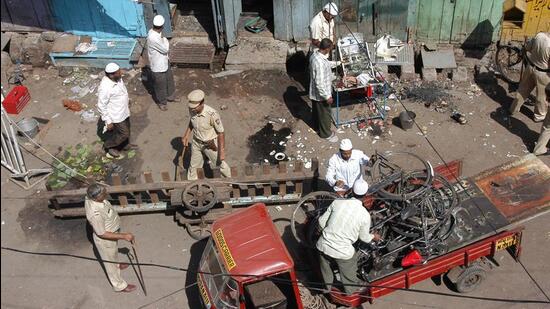 Local residents and police personnel clear debris at a blast site in Malegaon. Reuters File Photo
