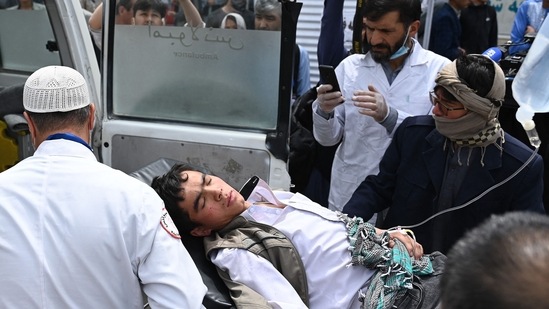 Medical staff move a wounded youth on a stretcher outside a hospital after three blasts rocked a boys' school in a Shiite Hazara neighbourhood in Kabul.(AFP)