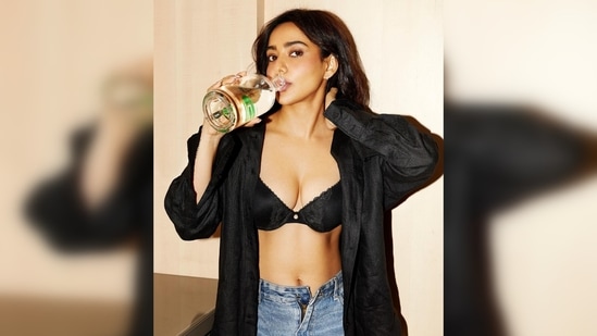 In another picture, Neha Sharma can be seen flaunting her toned abs in a black bra, unhooked denim and an oversized black shirt.(Instagram/@nehasharmaofficial)