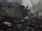 A man tries to extinguish a fire following a Russian bombardment at a residential neighborhood in Kharkiv, Ukraine (AP)