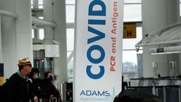 Travelers with and without masks walk around inside John F. Kennedy Airport on Tuesday in New York City.&nbsp;