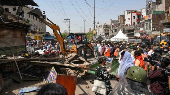 A bulldozer demolishes an illegal structure during an anti-encroachment drive in Jahangirpuri, New Delhi, on April 20, 2022. Several structures in Jahangirpuri were brought down amid heavy paramilitary and police presence during the North Delhi Municipal Corporation’s anti-encroachment drive that was stopped within hours following a Supreme Court order.(Amal KS / HT Photo)