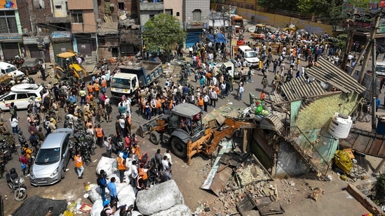An aerial view shows a bulldozer demolishing an illegal structure, in Jahangirpuri, New Delhi, on April 20, 2022. The demolition drive continued even after the apex court directed the authorities to stop it. Officials said it was because of the absence of a written order from the court.(Amal KS / HT Photo)