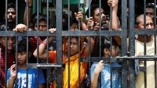 Residents watch the demolition of small illegal retail shops from behind the locked gate in a communally sensitive area in Jahangirpuri on April 20, 2022. (Reuters photo)