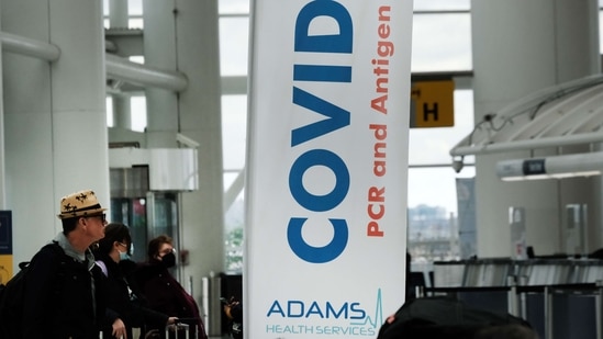 Travelers with and without masks walk around inside John F. Kennedy Airport on Tuesday in New York City.&nbsp;(AFP)