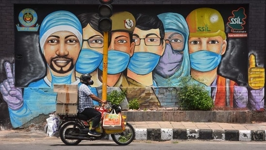 A motorist passes by a mural of frontline workers against coronavirus at RK Puram in New Delhi on July 25. Delhi’s Covid-19 recoveries have outstripped new cases on almost all days this month barring a few exceptions, after ramped-up containment and testing efforts over the past month or so. (Sanchit Khanna / HT Photo)