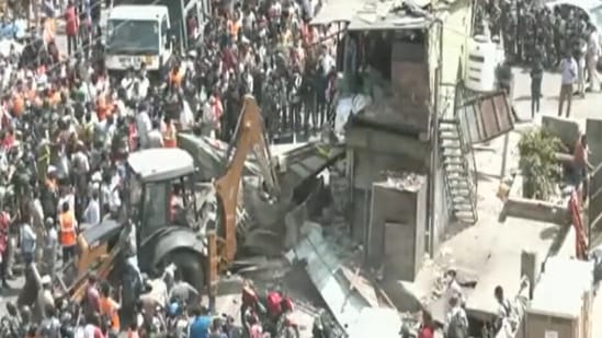A bulldozer can be seen taking down what appear to be roadside food stalls and shops.(ANI) A bulldozer can be seen taking down what appear to be roadside food stalls and shops.(ANI)