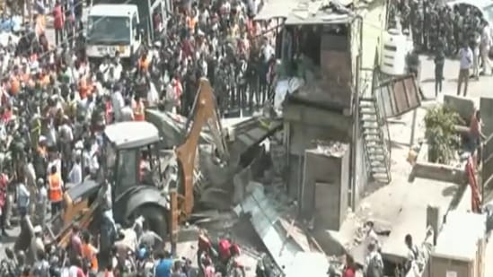 A bulldozer can be seen taking down what appear to be roadside food stalls and shops.