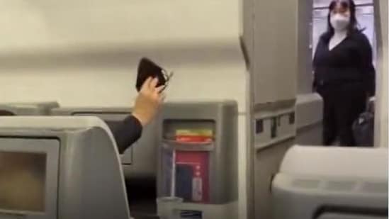 As the announcement was being made, a passenger took off the mask and waved in the air.&nbsp;(Screenshot from viral video/Bloomberg Quick Take)