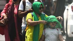 A mother covers the head of her child from the scorching heat at Dadar on Thursday. Satish Bate/HT Photo