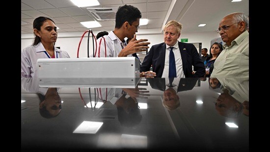 Britain's Prime Minister Boris Johnson listens to a student as the chief minister of India's Gujarat state Bhupendra Patel watches inside the laboratory of the Gujarat Biotechnology University, Gandhinagar, April 21, 2022 (AFP)