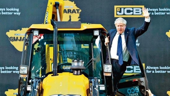 Britain's Prime Minister Boris Johnson waves from an excavator during his visit at the JCB factory in Vadodara, Gujarat, on April 21, 2022. (Photo by Stefan Rousseau/POOL/AFP)