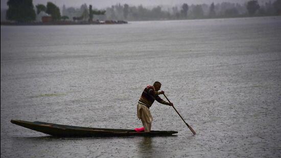 A man rows his boat at Dal Lake during rain in Srinagar on Thursday. (Waseem Andrabi/Hindustan Times)