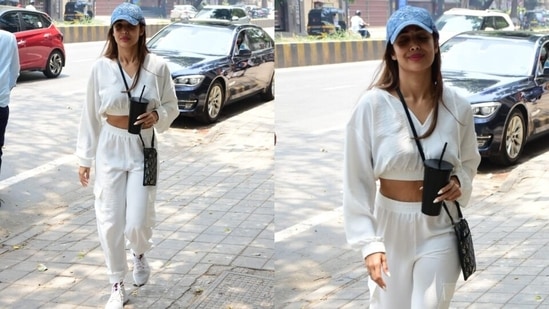 Malaika's hooded sweatshirt comes with a cropped length flaunting her toned abs, a V neckline with attached drawstrings, long sleeves with gathered cuffs, and a ribbed hem. She teamed it with matching white high-rise joggers with an elasticated waist, ribbed hem and patch pockets.(HT Photo/Varinder Chawla)