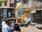 Local residents look on from their houses as a bulldozer demolishes an illegal structure during the anti-encroachment drive in Jahangirpuri, New Delhi, on April 20, 2022. (Amal KS / HT Photo)