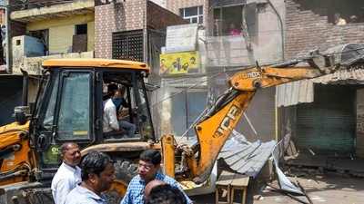 Local residents look on from their houses as a bulldozer demolishes an illegal structure during the anti-encroachment drive in Jahangirpuri, New Delhi, on April 20, 2022. (Amal KS / HT Photo) Local residents look on from their houses as a bulldozer demolishes an illegal structure during the anti-encroachment drive in Jahangirpuri, New Delhi, on April 20, 2022. (Amal KS / HT Photo)