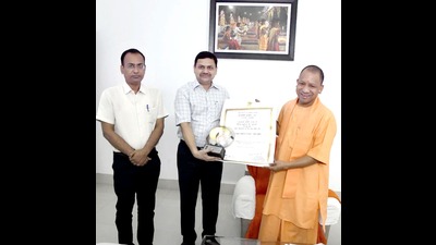 Divisional commissioner Deepak Agarwal and district magistrate Kaushal Raj Sharma handing over trophy and certificate of Prime Minister’s Award for Excellence in Public Administration 2021 to chief minister Yogi Adityanath (Sourced)