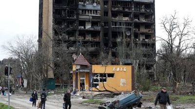People walk past a residential building heavily damaged during Ukraine-Russia conflict in the southern port city of Mariupol, Ukraine (REUTERS)