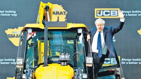 UK PM Boris Johnson waves from an excavator during his visit to the JCB factory in Vadodara.(AFP)