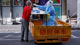 Um trabalhador médico em um traje de proteção coleta um cotonete de um residente para teste de ácido nucleico, em meio ao surto de doença por coronavírus (Covid-19) em Xangai, China.  (VIA REUTERS)