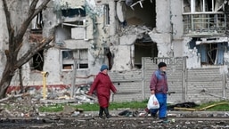 Pessoas caminham perto de um prédio residencial destruído durante o conflito Ucrânia-Rússia na cidade portuária de Mariupol, no sul, em 22 de abril de 2022. 