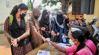 Students sanitise their hands and undergo thermal testing before appearing for the Karnataka Board exams, in Chikmagalur, on Friday. (PTI) Students sanitise their hands and undergo thermal testing before appearing for the Karnataka Board exams, in Chikmagalur, on Friday. (PTI)