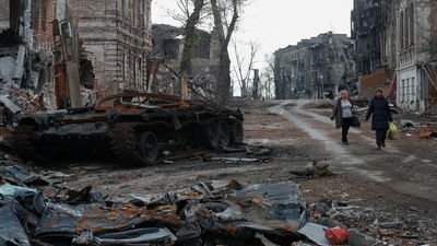 Ukraine war: People walk near a destroyed tank and damaged buildings in the course of Ukraine-Russia conflict in the southern port city of Mariupol,&nbsp; (REUTERS)