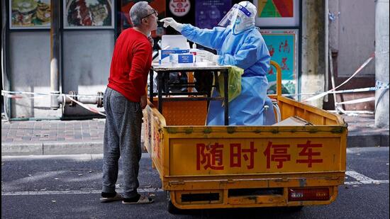 A medical worker in a protective suit collects a swab from a resident for nucleic acid testing, amid the coronavirus disease (Covid-19) outbreak in Shanghai, China. (VIA REUTERS)