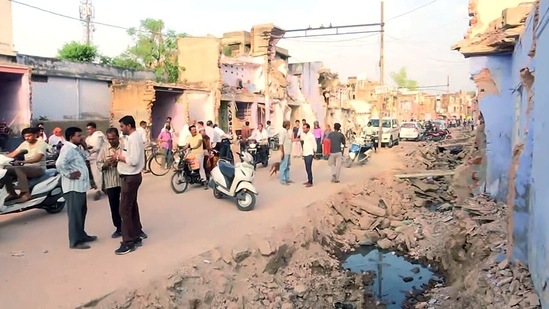 People gather at the incident site where a temple was demolished using a bulldozer in Alwar on Friday. (ANI Photo)