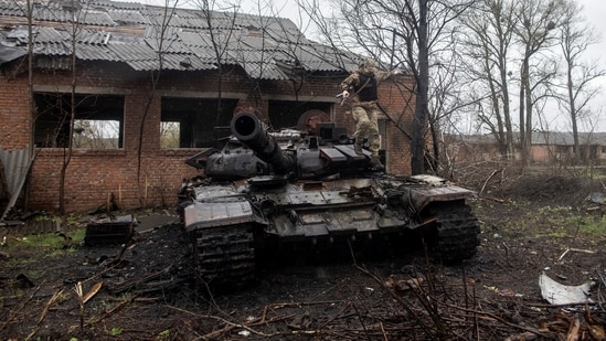 A Ukrainian soldier jumps of a destroyed Russian tank in Kharkiv region, Ukraine.(REUTERS)