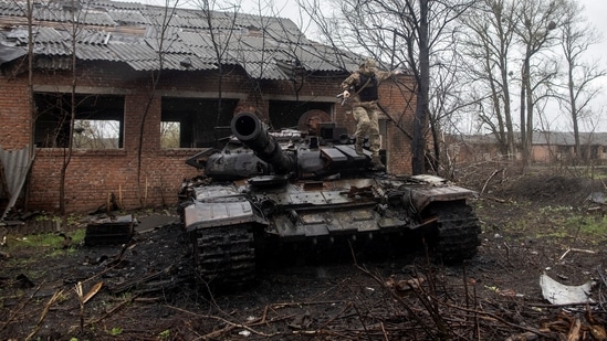 A Ukrainian soldier jumps of a destroyed Russian tank in Kharkiv region, Ukraine.(REUTERS)