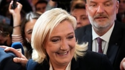 A líder de extrema-direita Marine Le Pen sorri ao sair depois de falar após o anúncio das primeiras projeções dos resultados do segundo turno das eleições presidenciais francesas.