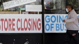 A man looks at signs of a closed store due to Covid-19 in US.