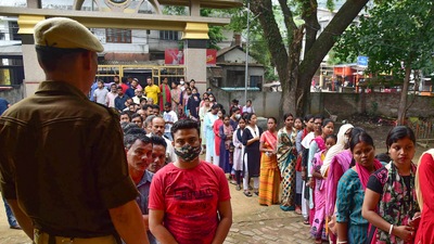 Guwahati: Security personnel keep vigil as voters wait in a queue to cast their votes for the Guwahati Municipal Election 2022, at Rupnagar in Guwahati, Friday, (PTI) Guwahati: Security personnel keep vigil as voters wait in a queue to cast their votes for the Guwahati Municipal Election 2022, at Rupnagar in Guwahati, Friday, (PTI)