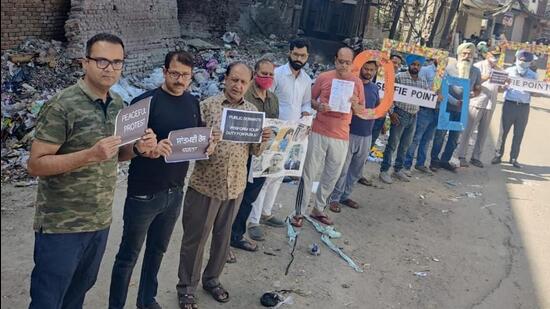 PAC members protesting in front of the open garbage dump at Saidan Chowk in Ludhiana on April 24. (Harvinder Singh/HT)