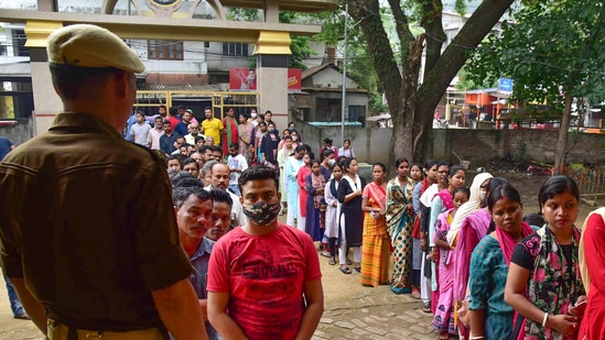 Guwahati: Security personnel keep vigil as voters wait in a queue to cast their votes for the Guwahati Municipal Election 2022, at Rupnagar in Guwahati, Friday, (PTI) Guwahati: Security personnel keep vigil as voters wait in a queue to cast their votes for the Guwahati Municipal Election 2022, at Rupnagar in Guwahati, Friday, (PTI)